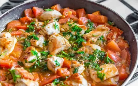 Succulento pollo alla pizzaiola in padella, con pomodoro fresco e prezzemolo. Un piatto saporito e invitante.