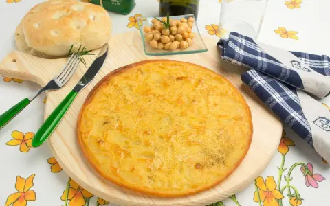 Una gustosa farinata di ceci in padella, pronta per essere gustata con pane fresco e un rametto di rosmarino.