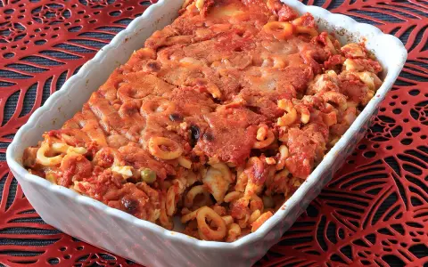 Un invitante piatto di anelletti al forno, con pasta corta condita con sugo rosso e formaggio gratinato, pronto per essere gustato.