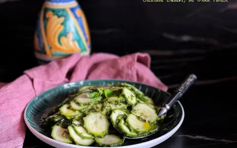 Fette di zucchine marinate crude, condite con erbe aromatiche e olio. Un contorno fresco e leggero, perfetto per l'estate.