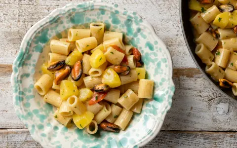 Un piatto di pasta patate e cozze, un classico della cucina italiana, servito in una ciotola decorata.