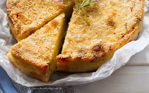 Delizioso gateau di patate dorato e croccante, guarnito con rosmarino fresco. Una fetta è già stata tagliata, invitando ad assaporare questo piatto saporito.