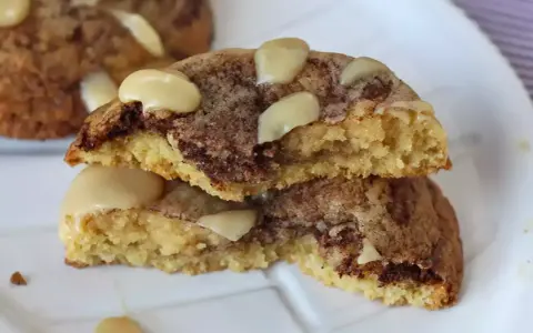 Biscotti alla cannella con gocce di cioccolato e mandorle, uno spezzato mostra l'interno morbido e profumato.