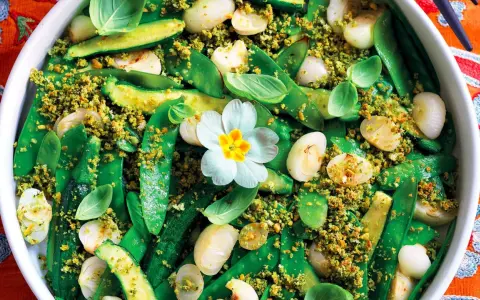 Un colorato contorno di verdure miste, con piselli, zucchine e cipolline, condito con pangrattato croccante. Un pranzo della domenica fatto in casa da Benedetta, con un fiore decorativo.