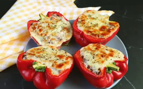 Quattro peperoni ripieni in friggitrice ad aria, con formaggio fuso e spezie, pronti per essere gustati.