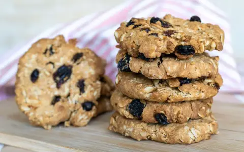 Una pila di biscotti integrali con uvetta e mandorle, perfetti biscotti senza zucchero per una pausa sana.