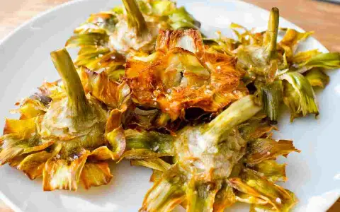 Carciofi fritti croccanti su un piatto bianco, un modo delizioso per imparare come cucinare i carciofi.