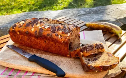Delizioso banana bread vegano con gocce di cioccolato e mandorle, pronto per essere gustato all'aperto.