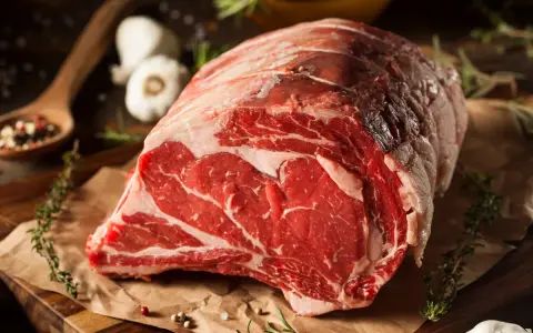 Un succulento pezzo di carne cruda, pronto per diventare un delizioso brasato di manzo. Spezie, erbe aromatiche e aglio completano la scena.