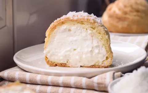 Bignè ripieno di crema soffice, cosparso di zucchero a velo che ricorda un fiocco di neve.