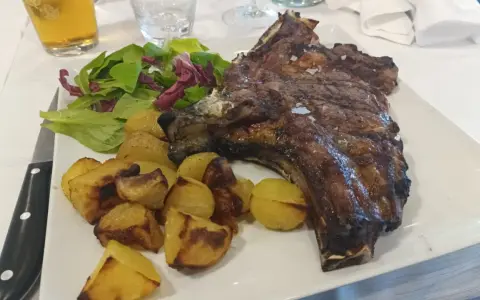 Costata di manzo succulenta con patate arrosto e insalata fresca, un piatto da re.
