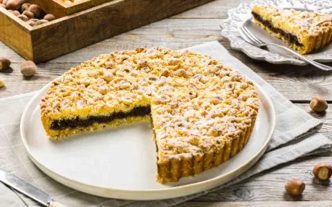 Sbriciolata alla Nutella con tante nocciole croccanti, un dolce invitante su un piatto bianco, pronto per essere gustato.