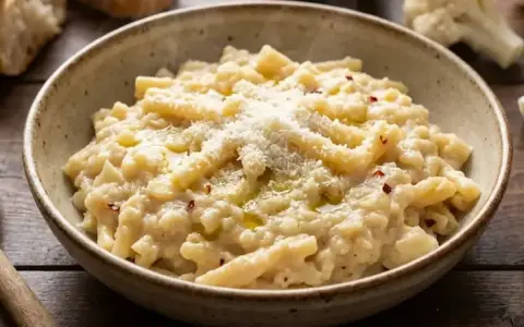 Un piatto fumante di pasta e cavolfiore cremoso, condito con parmigiano e peperoncino.