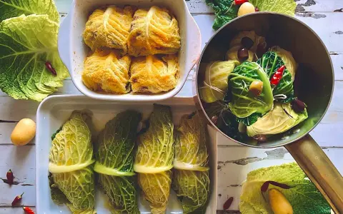 Involtini di verza pronti per essere cotti, alcuni impanati, altri legati con filo, con patate e peperoncini intorno.