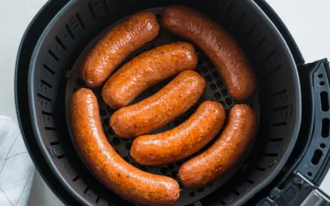 Salsiccia dorata e succulenta in friggitrice ad aria, pronta per essere gustata.