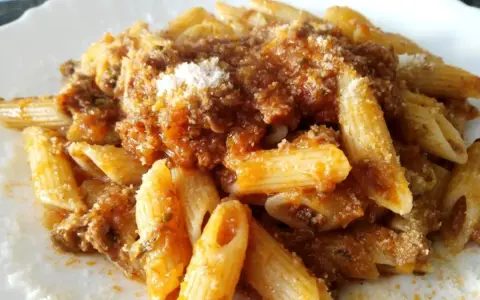Penne al ragù di cinghiale, un piatto ricco e saporito, condito con abbondante sugo e una spolverata di parmigiano.