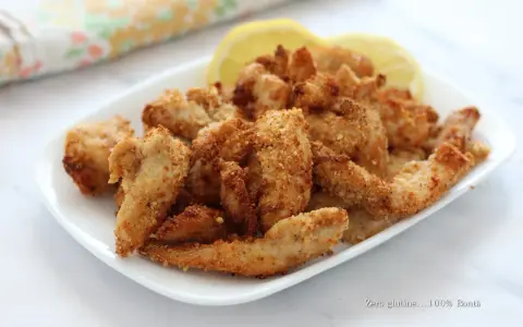 Straccetti di pollo in friggitrice ad aria, croccanti e dorati, serviti con spicchi di limone. Perfetti per un pasto leggero e gustoso.