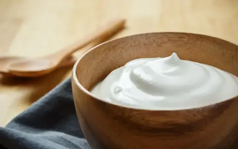 Una ciotola di legno contiene una soffice crema al latte, pronta per essere gustata.