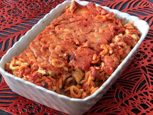 Un invitante piatto di anelletti al forno, con pasta corta condita con sugo rosso e formaggio gratinato, pronto per essere gustato.