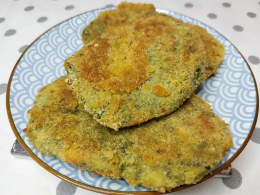 Tre spinacine fatte in casa, dorate e croccanti, servite su un piatto blu con decorazioni a onde.