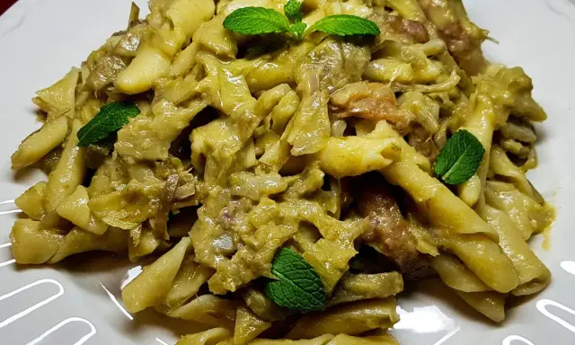 Un piatto invitante di pasta con carciofi, condita con erbe fresche, pronta per essere gustata.