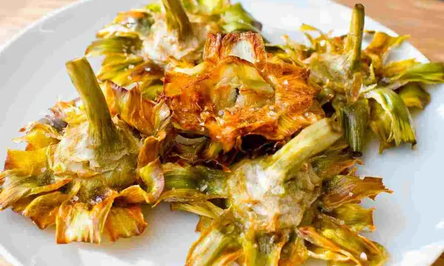Carciofi fritti croccanti su un piatto bianco, un modo delizioso per imparare come cucinare i carciofi.