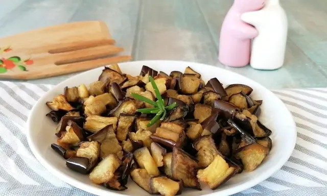Melanzane in friggitrice ad aria, dorate e saporite, pronte per essere gustate. Un rametto di rosmarino le impreziosisce.