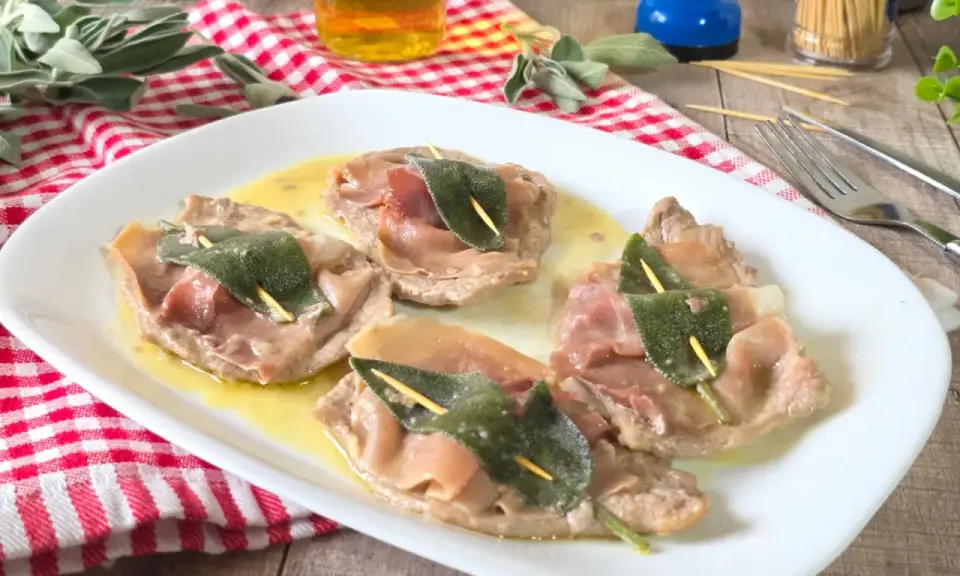Saltimbocca alla romana: fettine di vitello con prosciutto e salvia, servite su un piatto bianco con salsa dorata.
