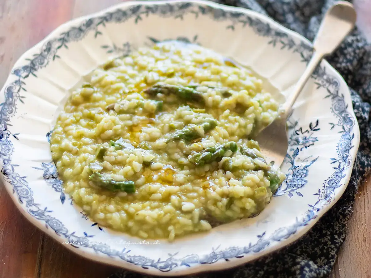Un cremoso risotto con asparagi, servito in un piatto decorato con un motivo blu. Un piatto primaverile invitante.