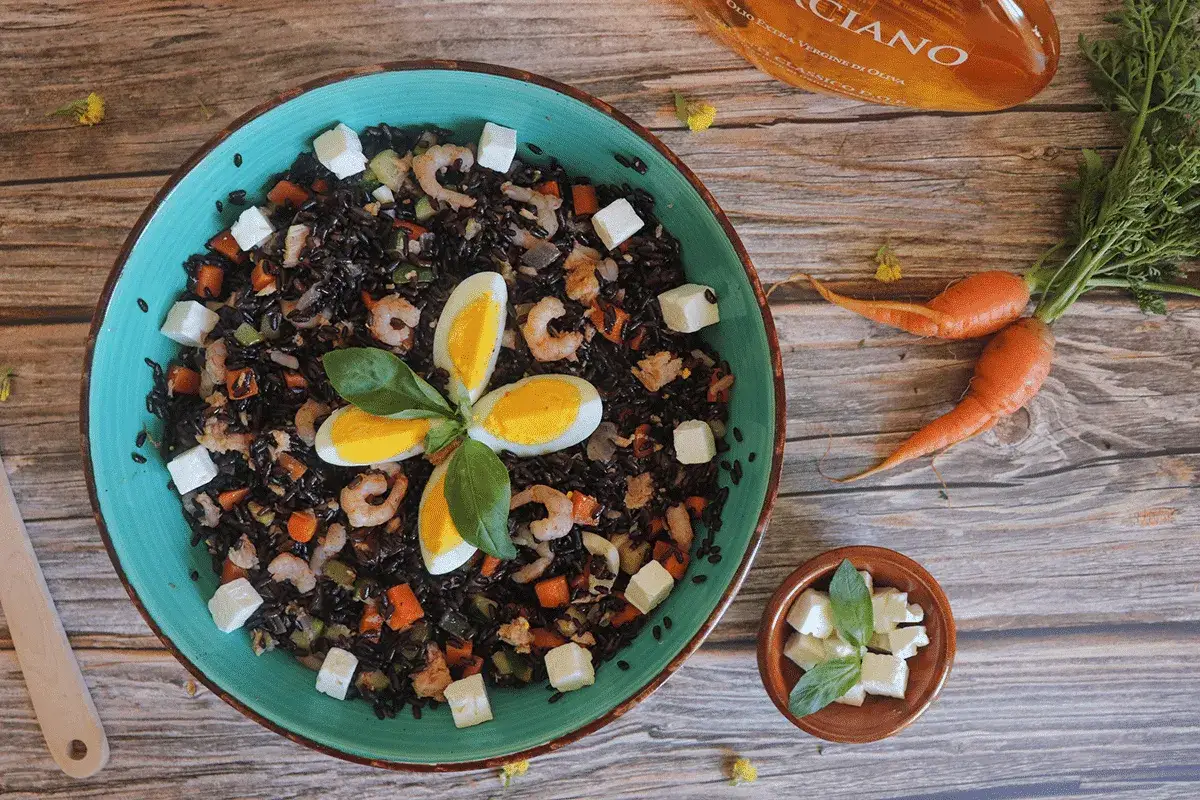 Deliziosa insalata di riso nero con gamberetti, uova sode a fiore, cubetti di formaggio e verdure. Un piatto colorato e gustoso.