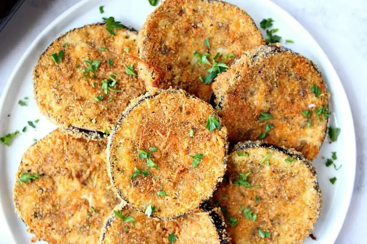 Fette dorate di melanzane impanate al forno, guarnite con prezzemolo fresco. Un antipasto leggero e gustoso.