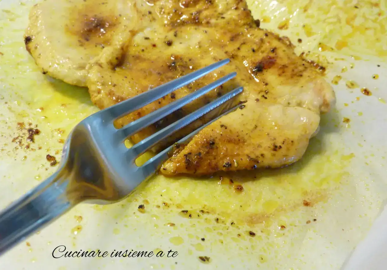 Un succulento petto di pollo cotto, condito con spezie, pronto per essere gustato con una forchetta.
