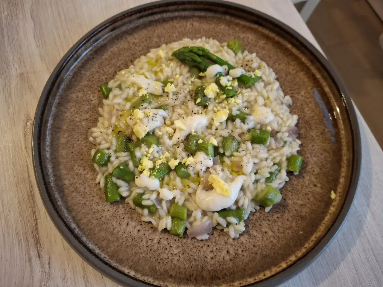 Risotto cremoso con asparagi freschi, pezzetti di uovo sodo e un filo d'olio. Un piatto primaverile da gustare.