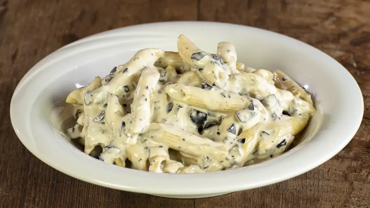 Penne cremose con olive nere, un piatto di pasta alla cenere che invita a gustare ogni boccone.