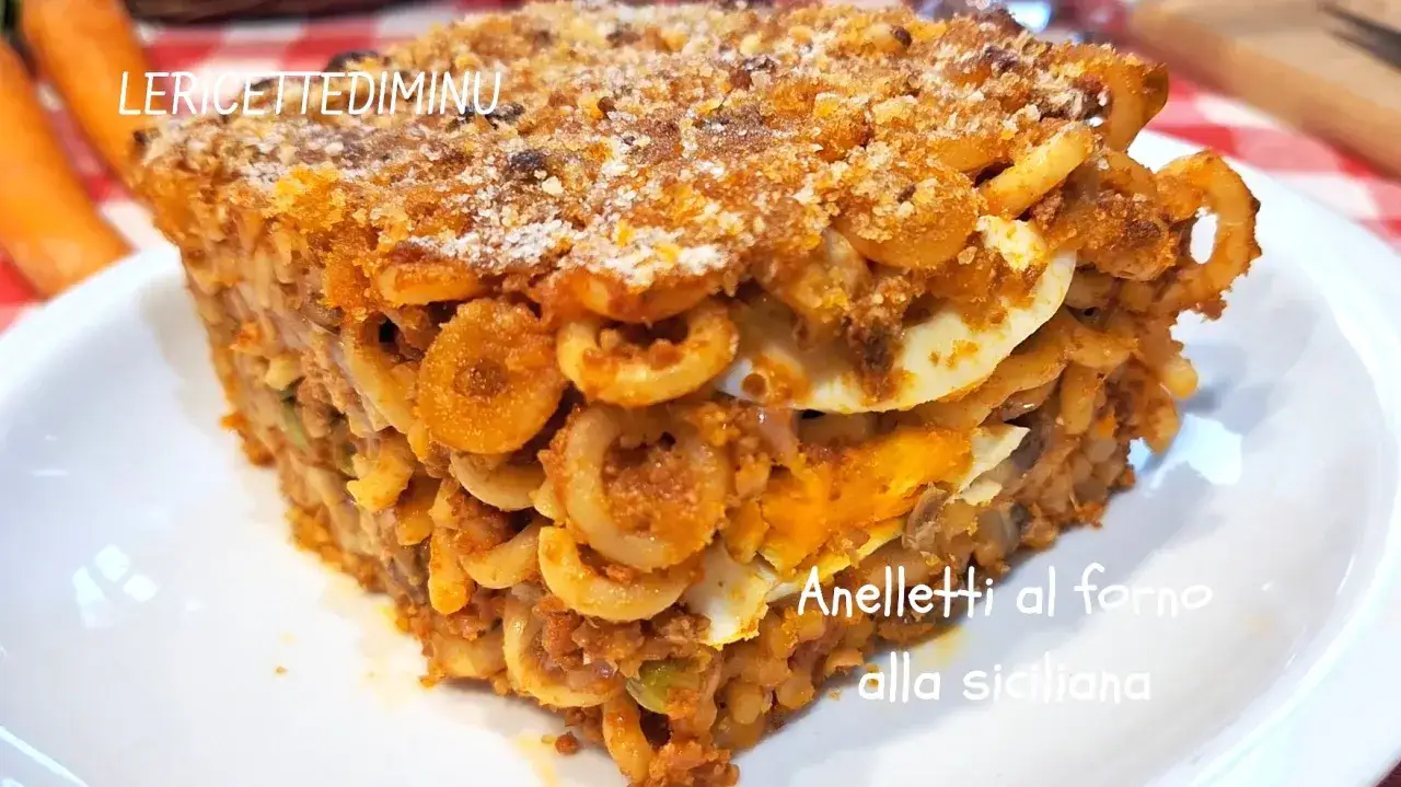 Porzione di anelletti al forno alla siciliana, con strati di pasta, ragù e uova sode, dorata in superficie.