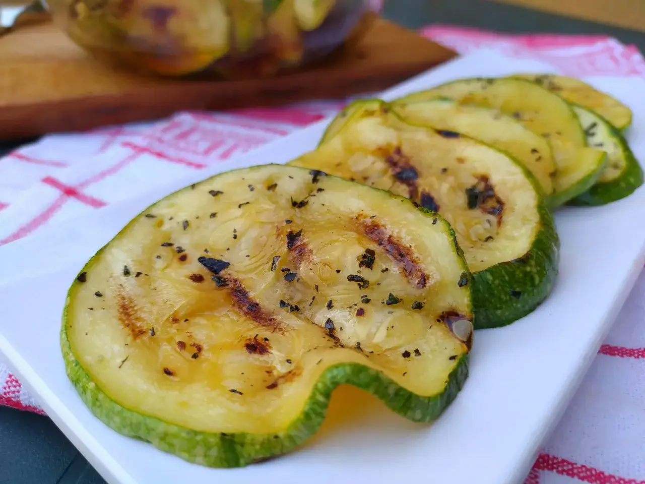 Fette di zucchine grigliate, condite con erbe aromatiche, pronte per essere gustate. Un modo semplice per scoprire come cucinare le zucchine.
