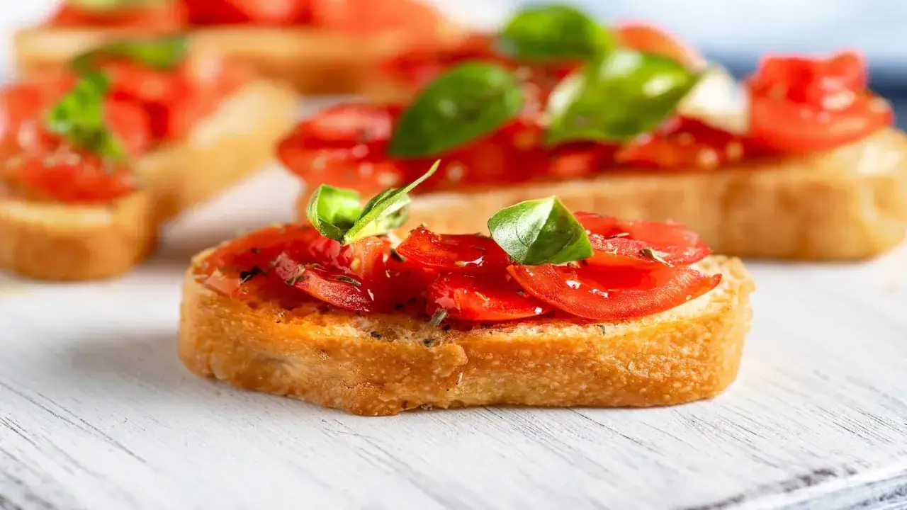 Bruschetta al pomodoro: fette di pane tostato croccante con pomodorini freschi, basilico e un filo d'olio.