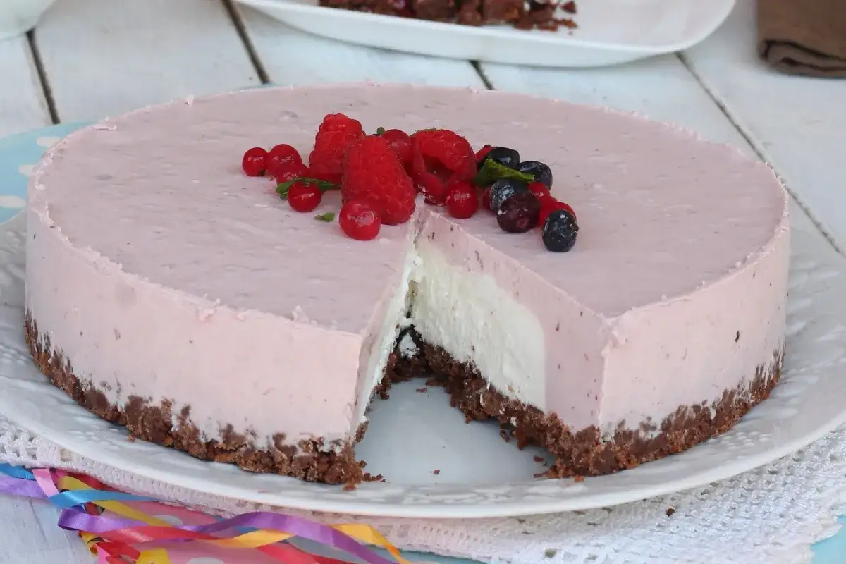 Delizioso cheesecake allo yogurt con base croccante e decorato con frutti di bosco freschi.