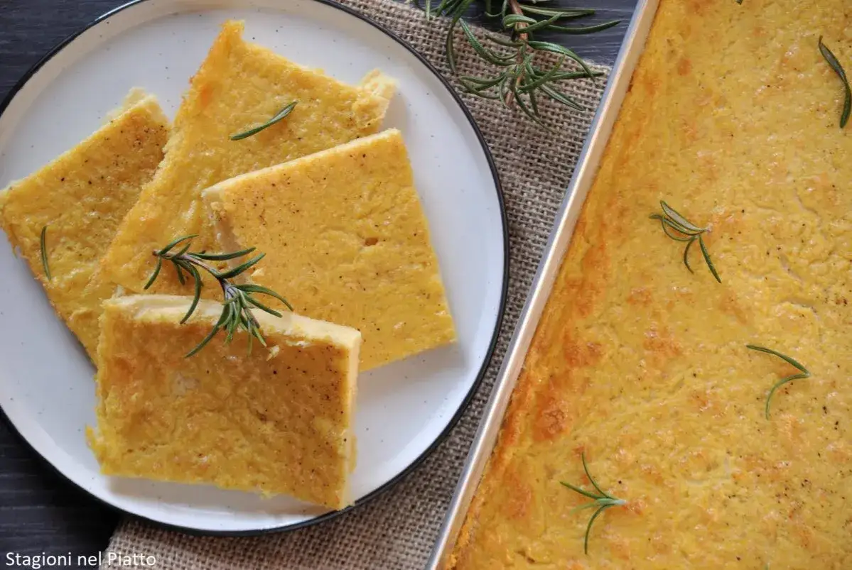 Farinata di ceci in padella, dorata e profumata al rosmarino, servita su un piatto bianco.