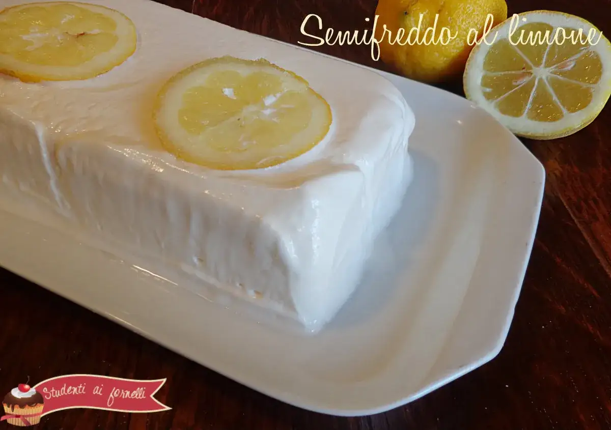 Un delizioso semifreddo al limone, guarnito con fette di limone, su un piatto bianco.