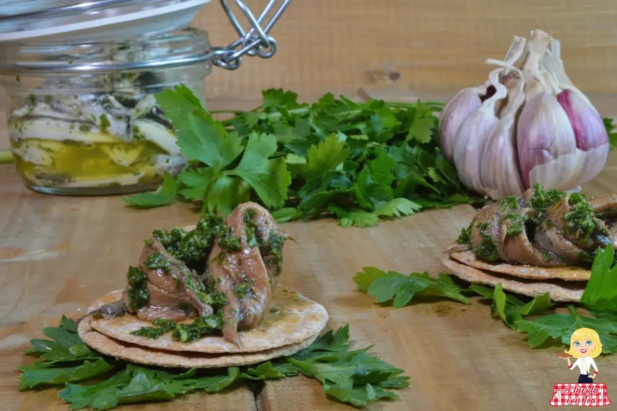 Acciughe al verde su crostini, con aglio e prezzemolo fresco. Un antipasto saporito e facile da preparare.