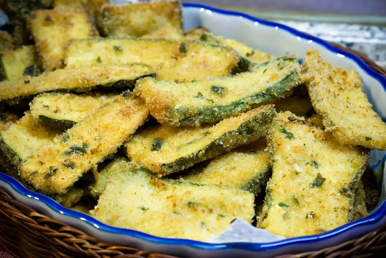 Fettine dorate di zucchine in padella, croccanti e saporite, pronte per essere gustate.