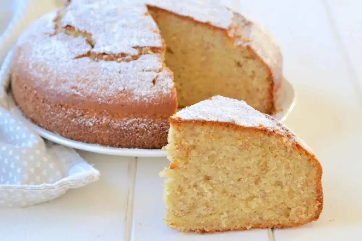Una soffice torta di banane, cosparsa di zucchero a velo, con una fetta tagliata e pronta per essere gustata.