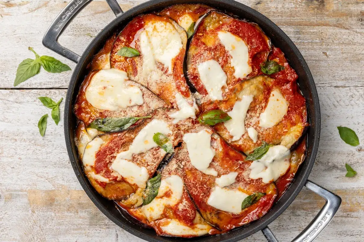 Parmigiana di melanzane al forno, un classico intramontabile, con strati di melanzane, sugo rosso, mozzarella filante e basilico fresco.