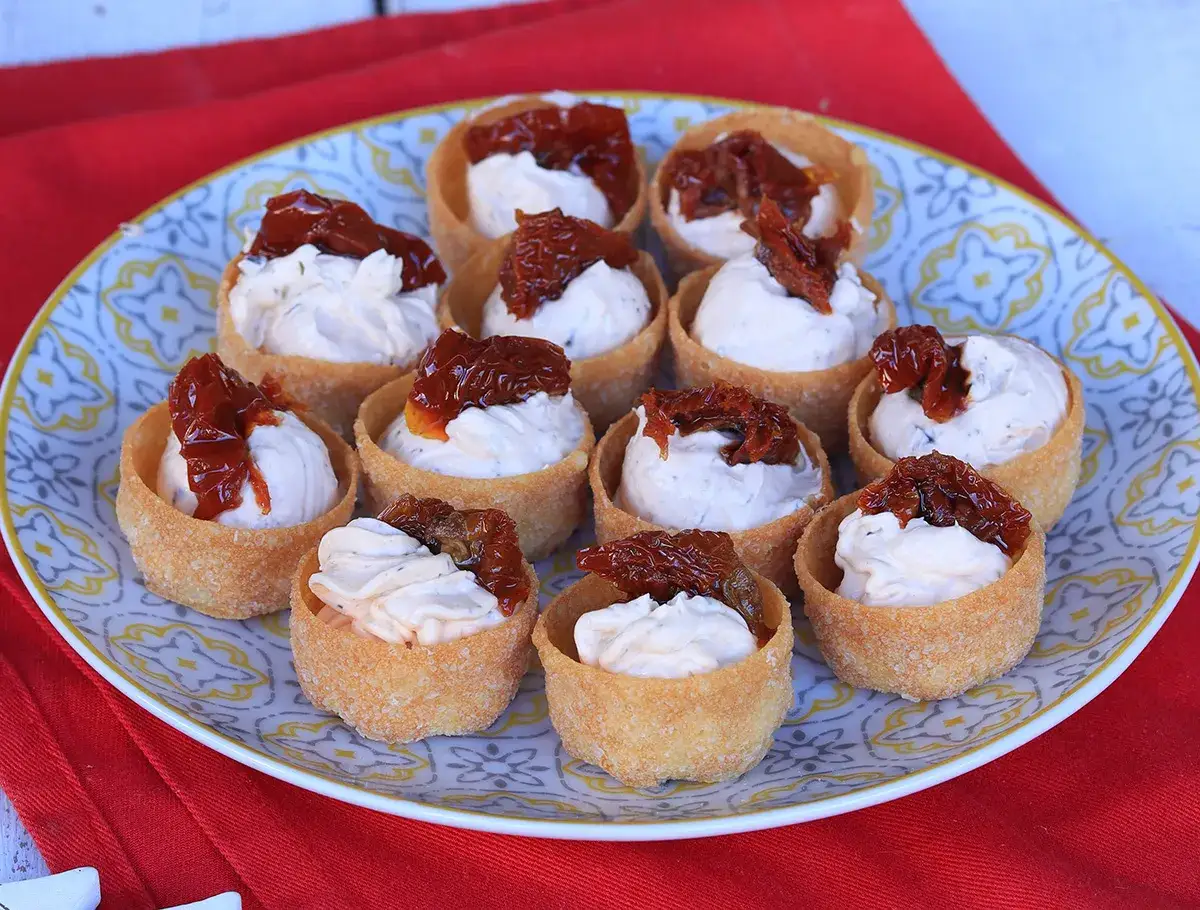 Antipasti veloci ed economici senza cottura: cestini croccanti ripieni di crema e pomodori secchi.