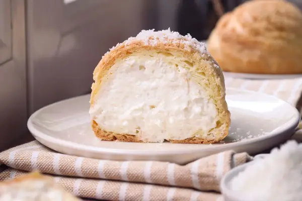 Bignè ripieno di crema soffice, cosparso di zucchero a velo che ricorda un fiocco di neve.