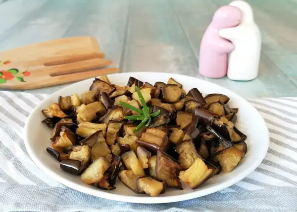 Melanzane in friggitrice ad aria, dorate e saporite, pronte per essere gustate. Un rametto di rosmarino le impreziosisce.