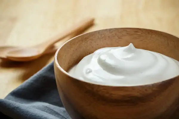 Una ciotola di legno contiene una soffice crema al latte, pronta per essere gustata.