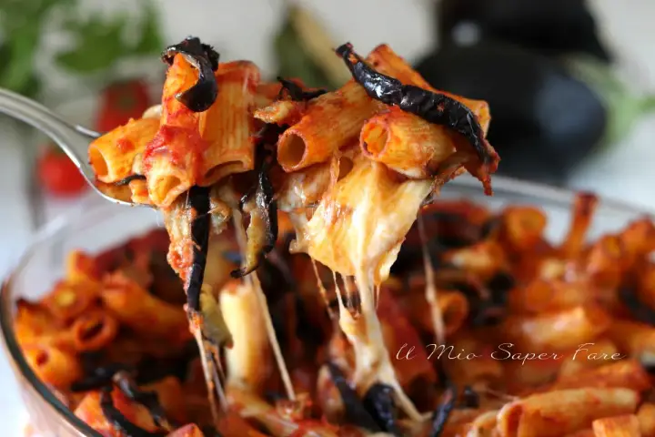 Un primo piatto fumante di pasta alla norma, con melanzane fritte, pomodoro e tanto formaggio filante che si allunga.