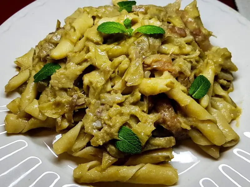 Un piatto invitante di pasta con carciofi, condita con erbe fresche, pronta per essere gustata.